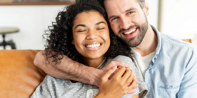 Lovely multiracial couple in embraces in cozy living room at home