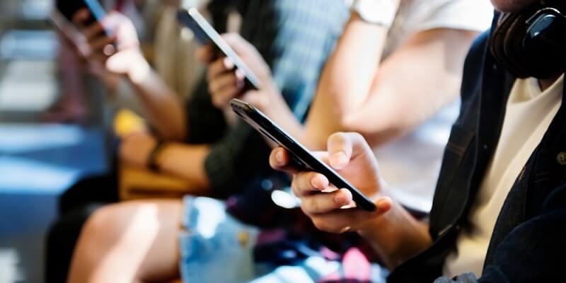 Group of young adult friends using smartphones