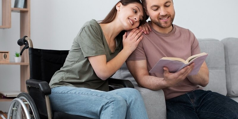 Man reading book with his disabled girlfriend