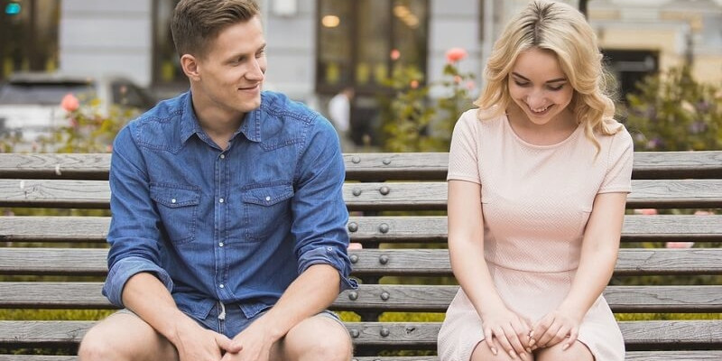 Shy guy flirting with beautiful woman on bench