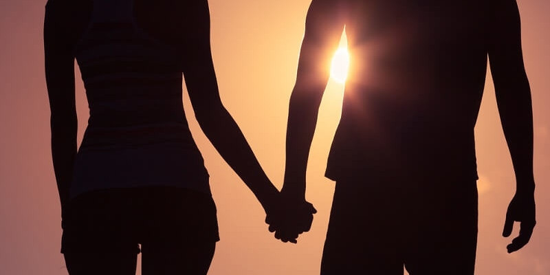 Silhouette of man woman holding hands