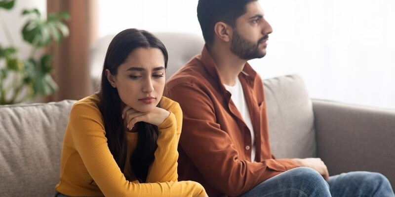 Unhappy Couple Sitting On Couch At Home