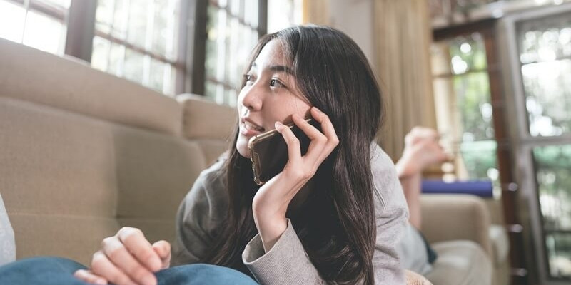 Woman laying on sofa using phone calling someone