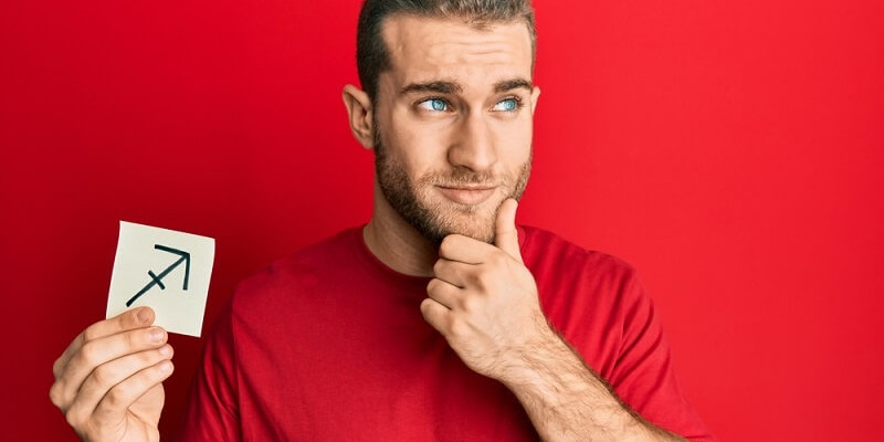 man holding paper with sagittarius zodiac sign