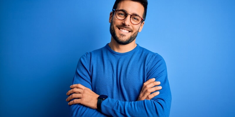 man with beard wearing casual sweater and glasses smiling with crossed arms