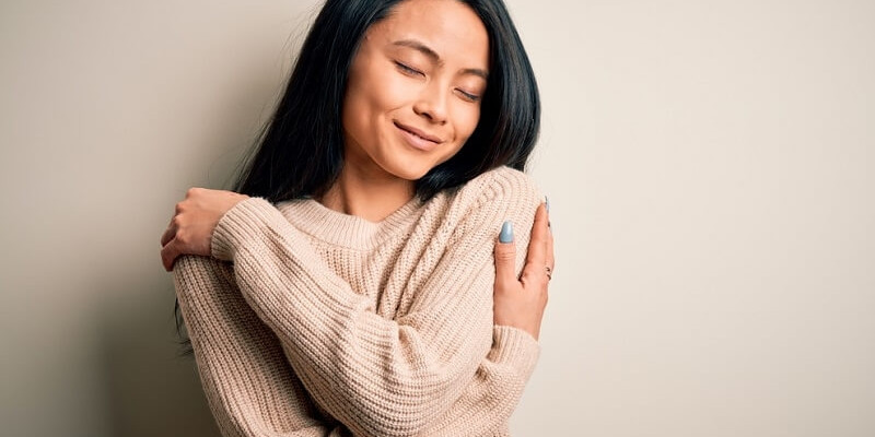 woman wearing sweater Hugging oneself happy and positive selfcare