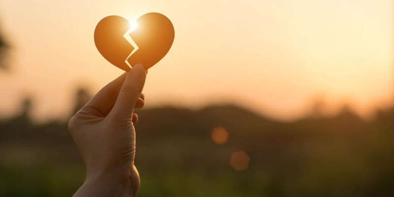 A close up woman hand holding broken heart in the park