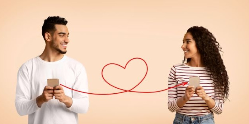 man and woman smiling at each other while holding phones, connected by a red heart line, illustrating dating app etiquette