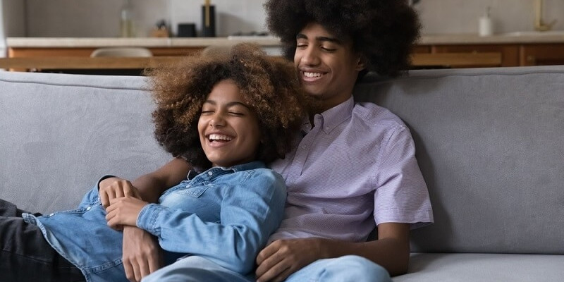 a girl and boy relaxing on sofa and spending time  happily with each other
