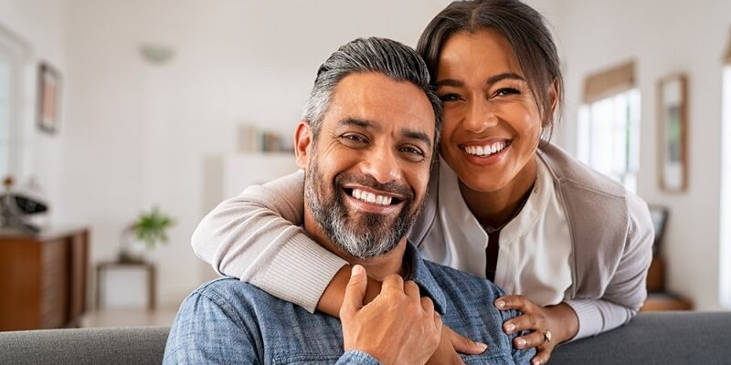 Woman hugging man from behind sitting on couch